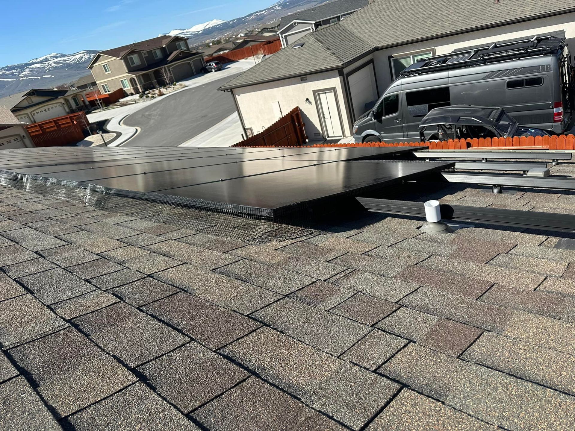 A van is parked on the roof of a house next to a solar panel.