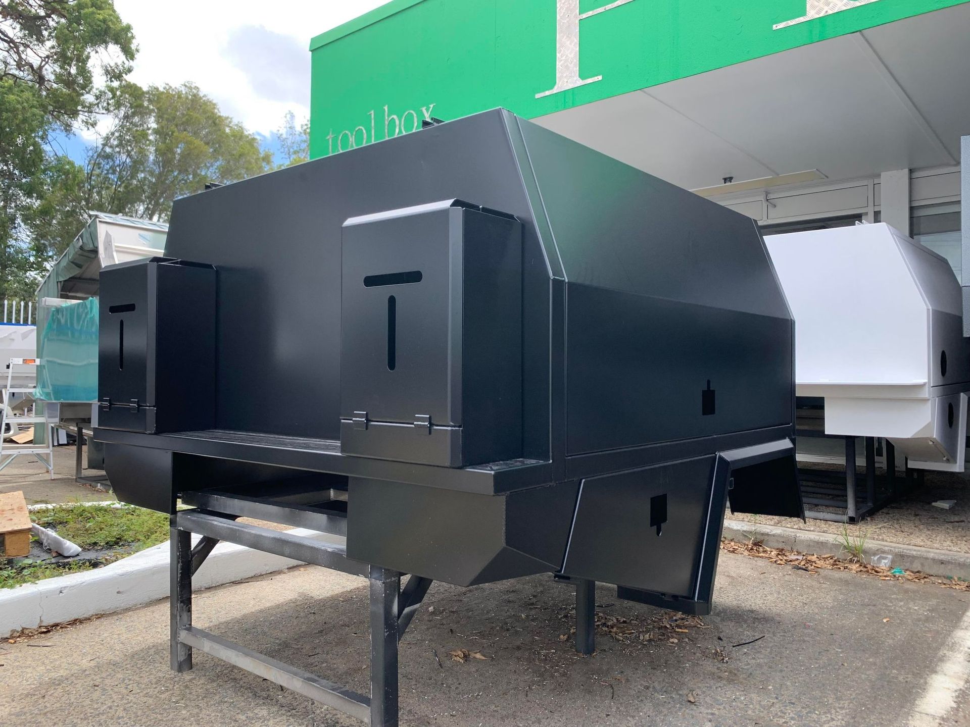 Black Truck Bed Canopy on a Stand Outside a Store With a Green Sign — PT Canopy In Slacks Creek, QLD