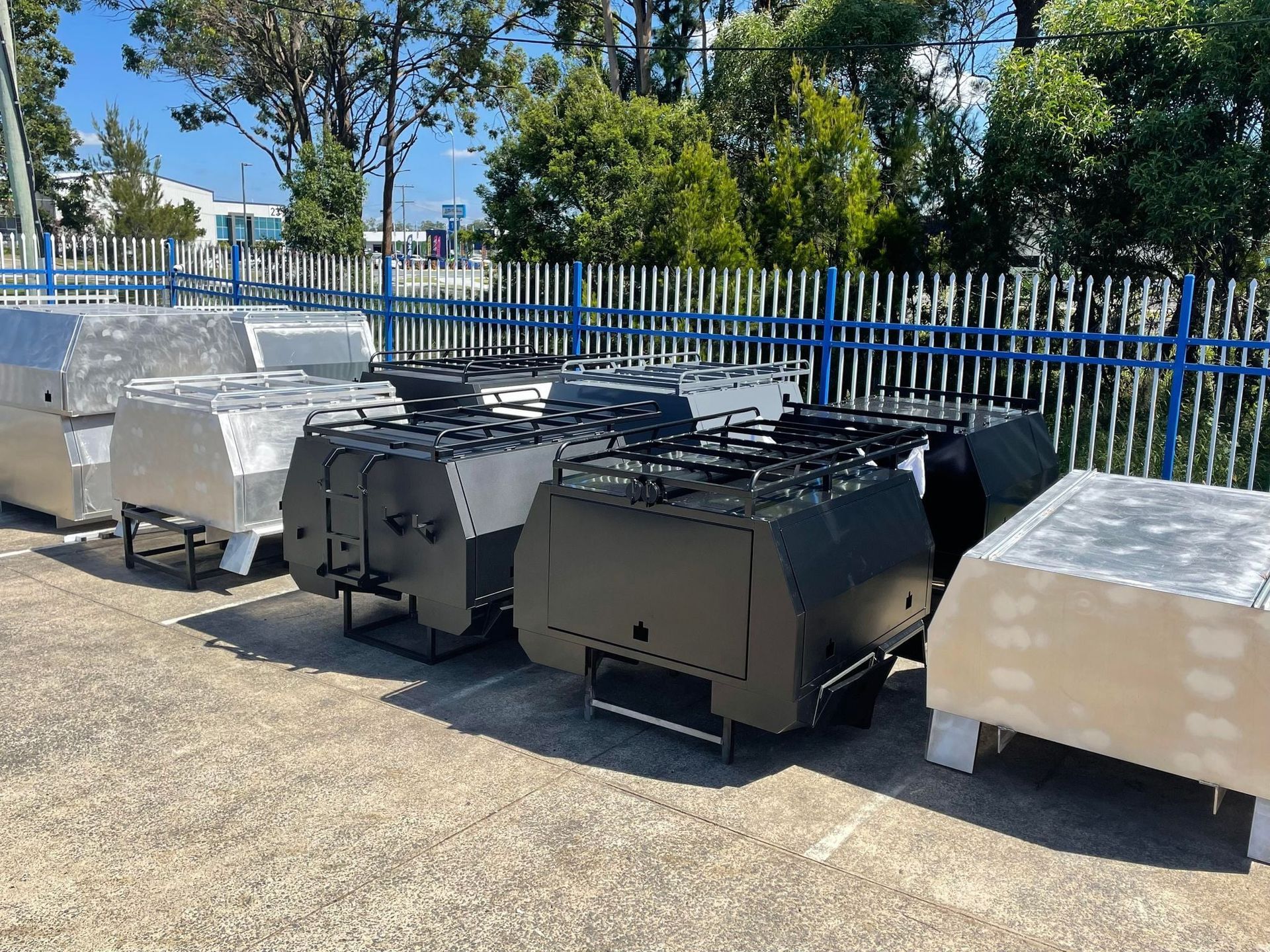Several Vehicle Utility Boxes in Various Colors Parked Outside Behind Fence — PT Canopy In Slacks Creek, QLD