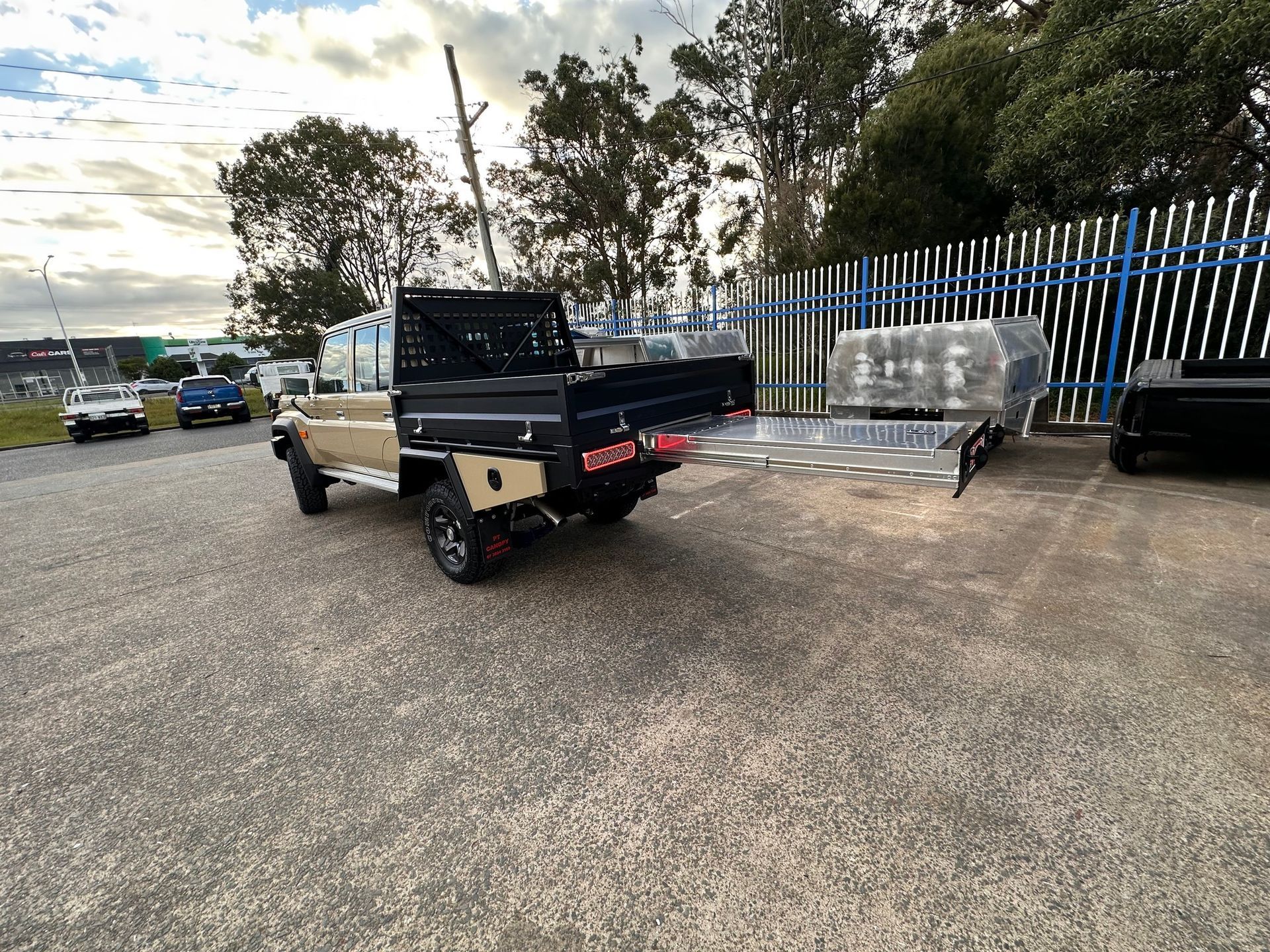 Tan Utility Truck With a Black Tray Parked on Gravel Next to a Trailer and a Fence — PT Canopy In Slacks Creek, QLD