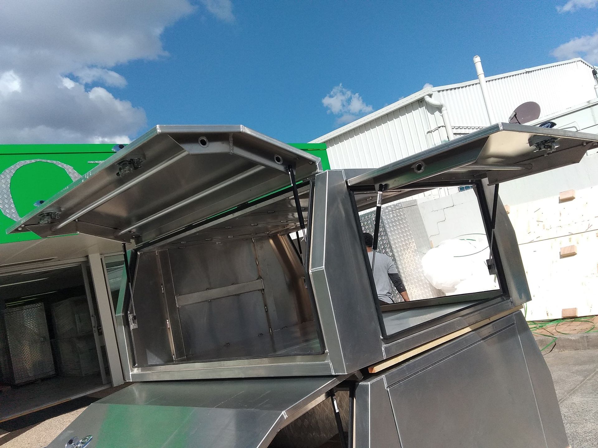 Two Silver Truck Canopies With Open Lids Against a Blue Sky — PT Canopy In Slacks Creek, QLD