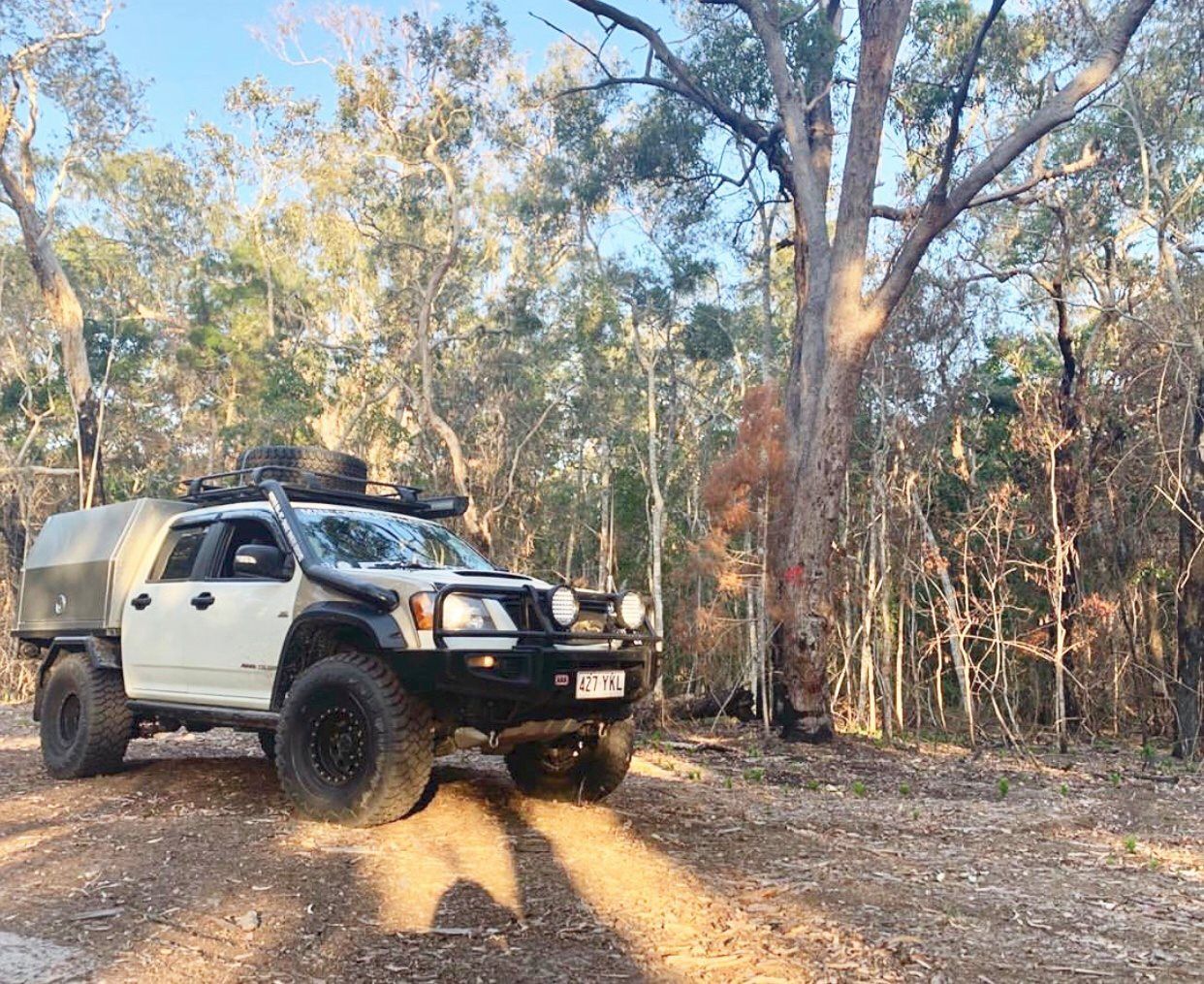 White and Black 4x4 Truck With Camping Accessories Parked on a Dirt Road Surrounded by Trees — PT Canopy In Slacks Creek, QLD