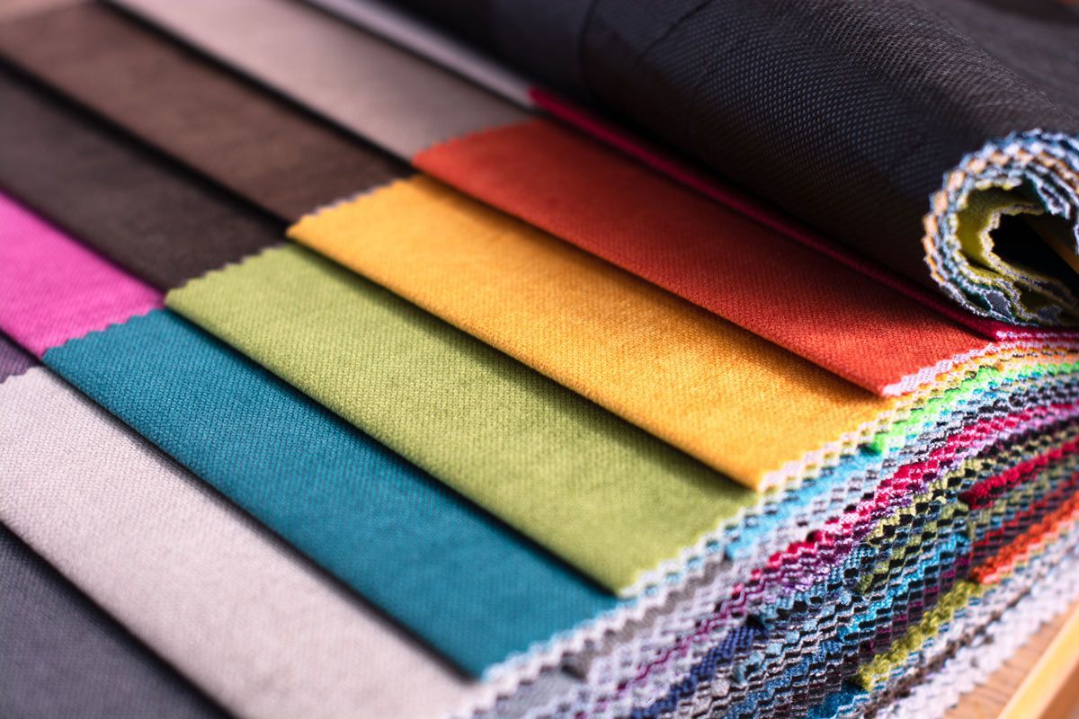 A bunch of different colored fabrics are stacked on top of each other on a table