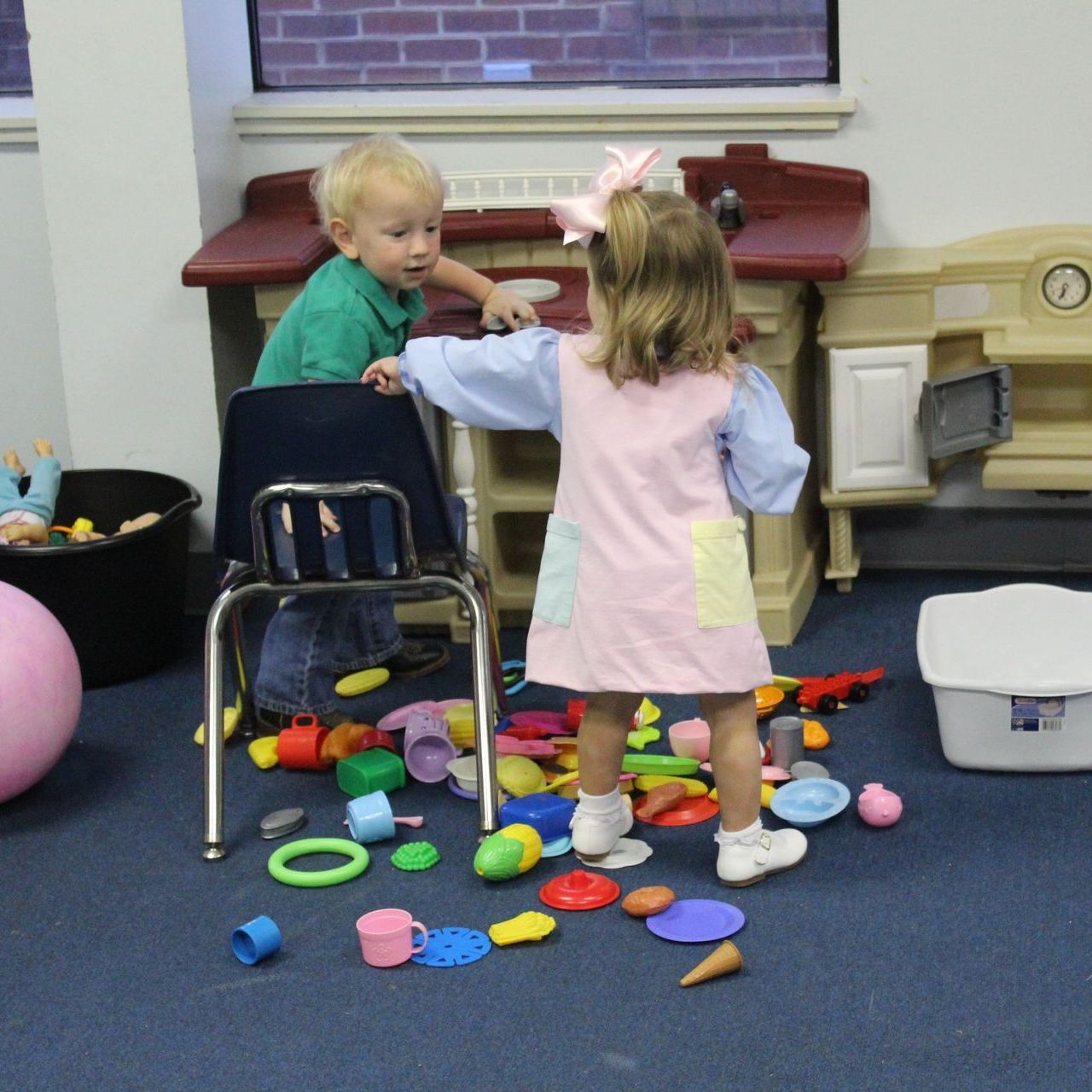 A boy and a girl are playing with toys in a room