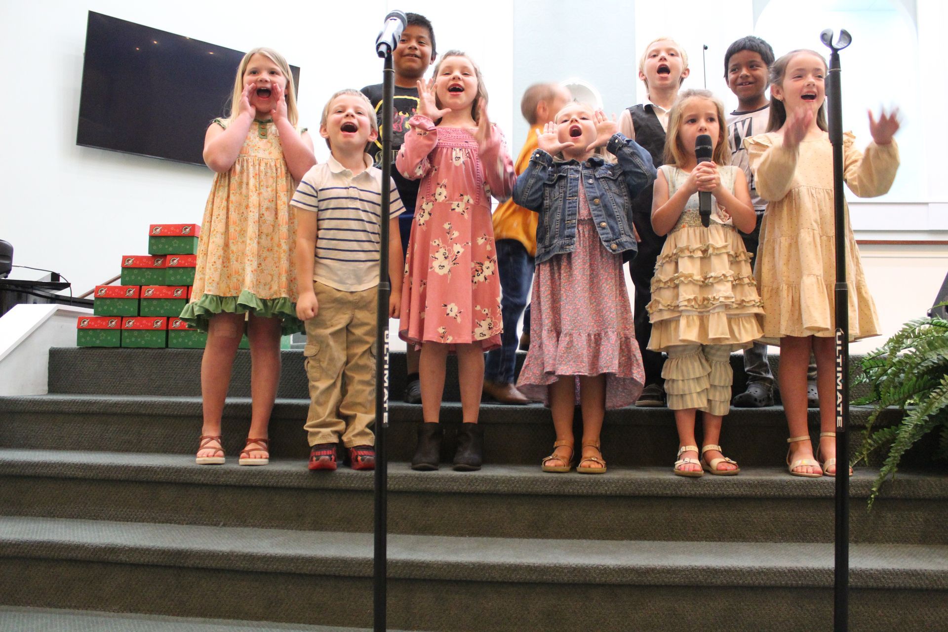 A group of children singing into microphones on a stage