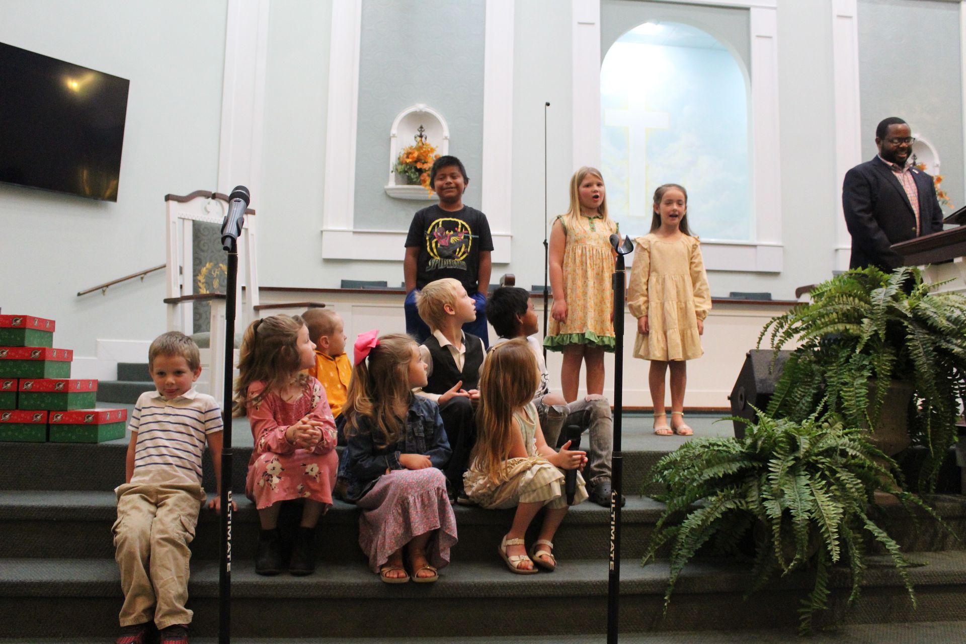 A group of children are sitting on the steps of a church.