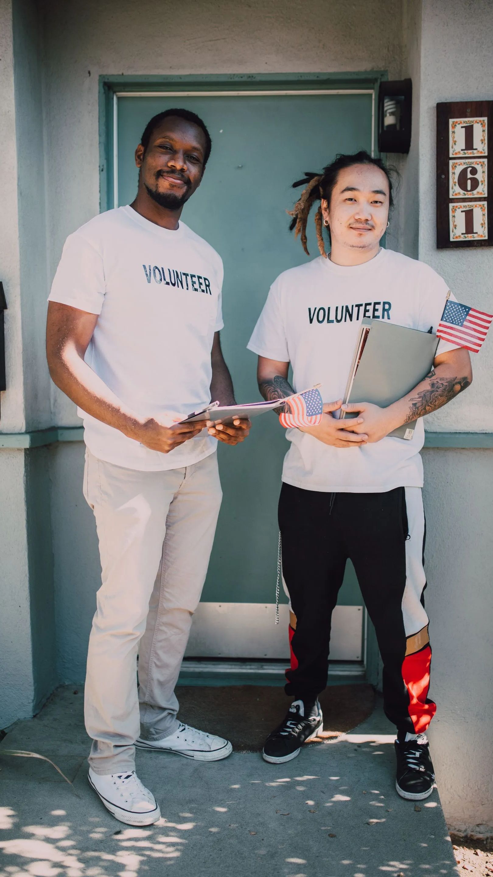 Two men are standing next to each other in front of a door.