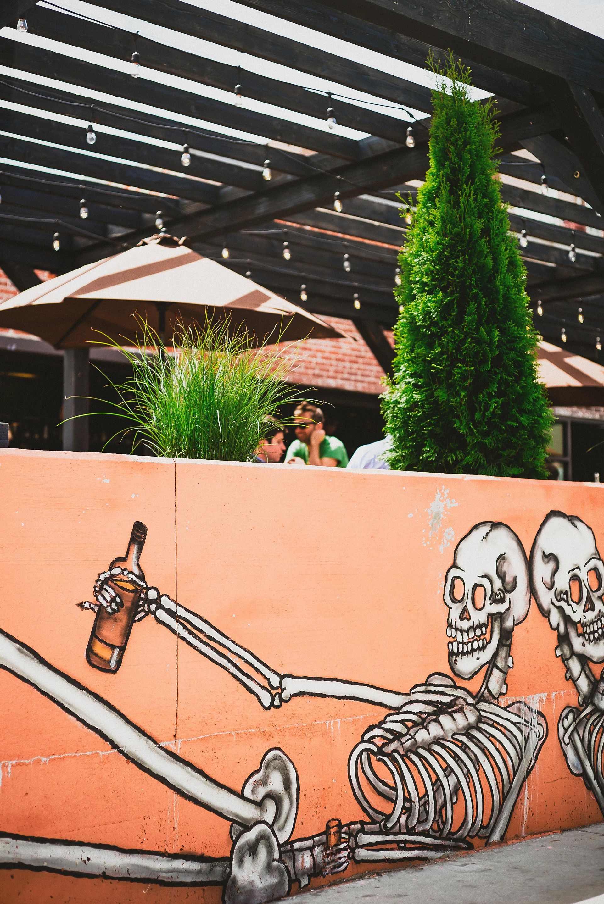 Orange wall with skeleton graffiti, outdoor restaurant scene.