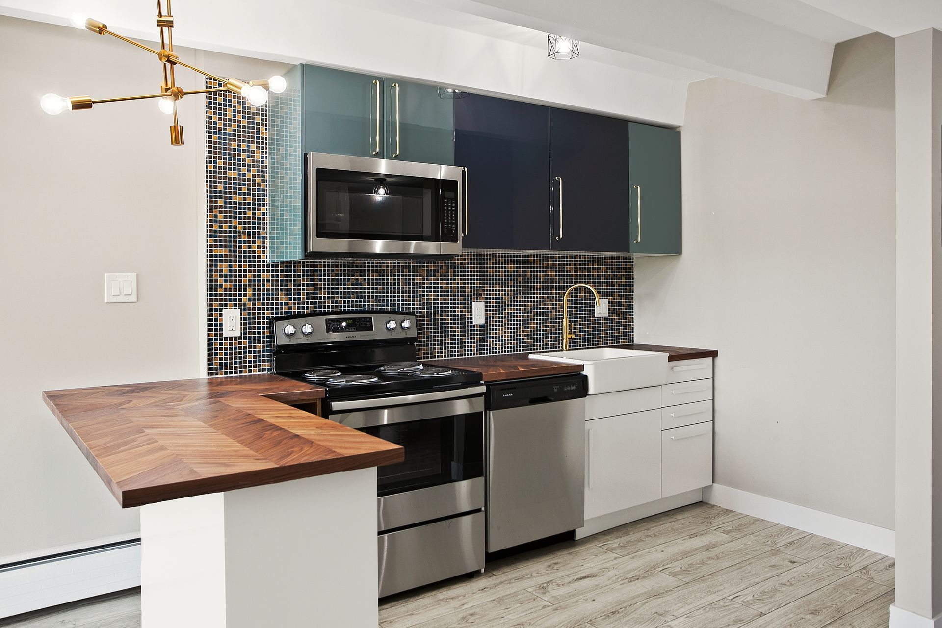Small modern kitchen with a stainless steel stove, wood countertop, and blue and glass cabinets.