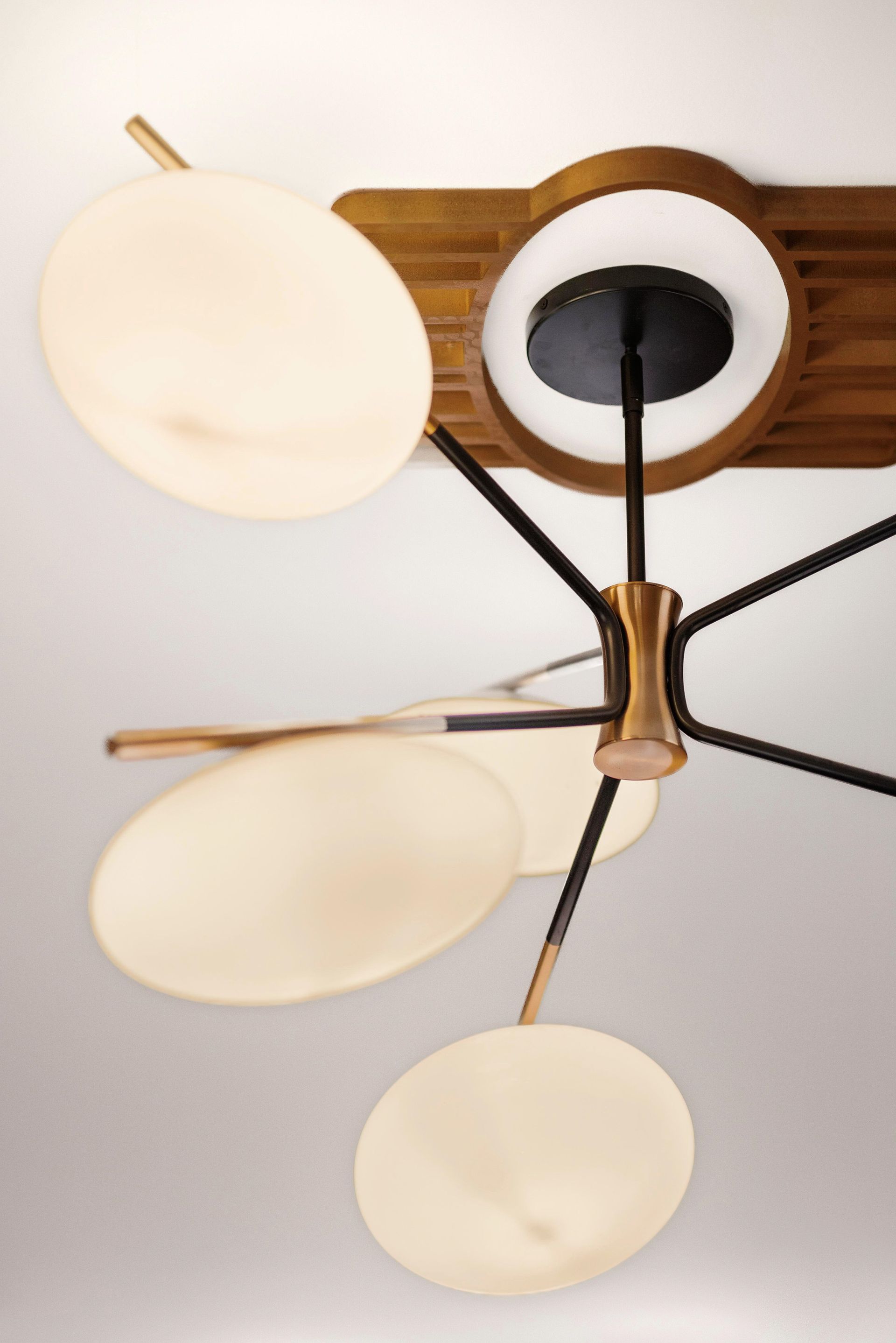 Modern ceiling light fixture with oval, diffused white shades, gold and black accents.