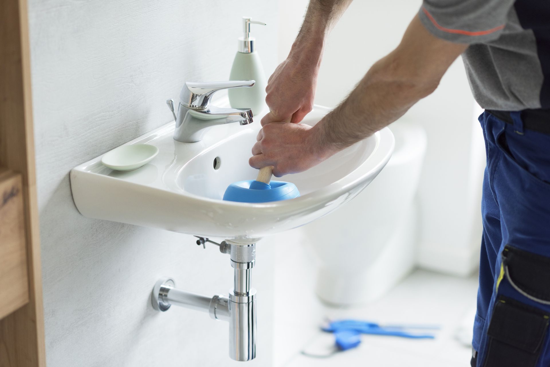 Plumber Using a Plunger to Unblock a Sink — Teaneck, NJ — Marvin Newman Plumbing & Heating