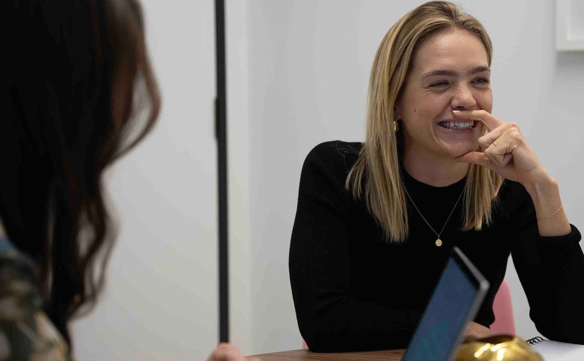 A Finance Recruiter & a Talent sitting at a table with laptops and talking to each other