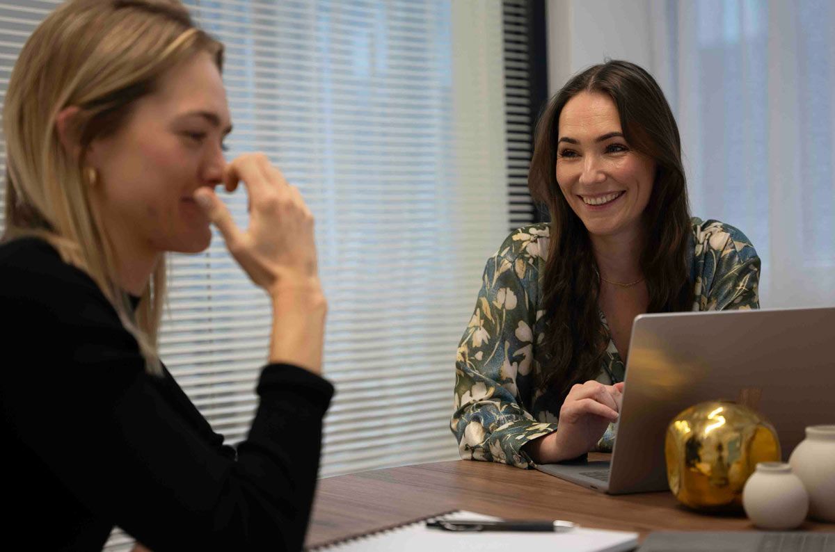 Two Product & Design recruiters are sitting at a table with a laptop