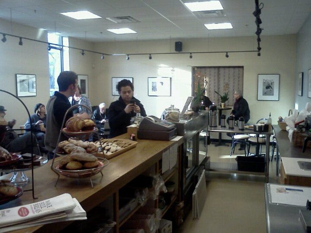 A group of people are gathered around a counter in a restaurant with a sign that says ' iowa ' on it