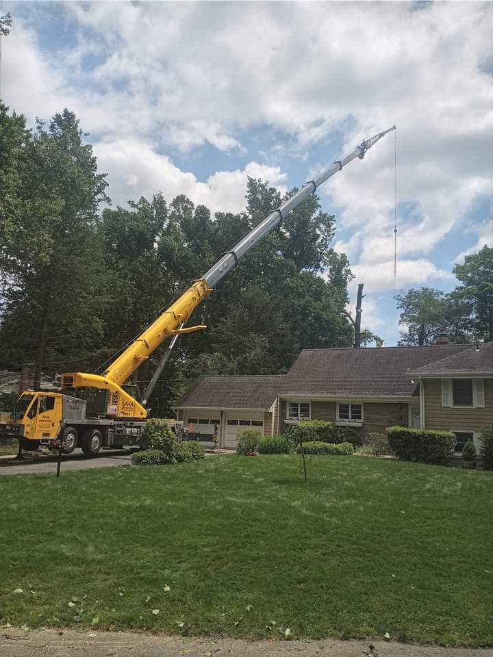 A person operates a crane basket with a control panel. They wear a tan uniform and sunglasses, and the crane is white.