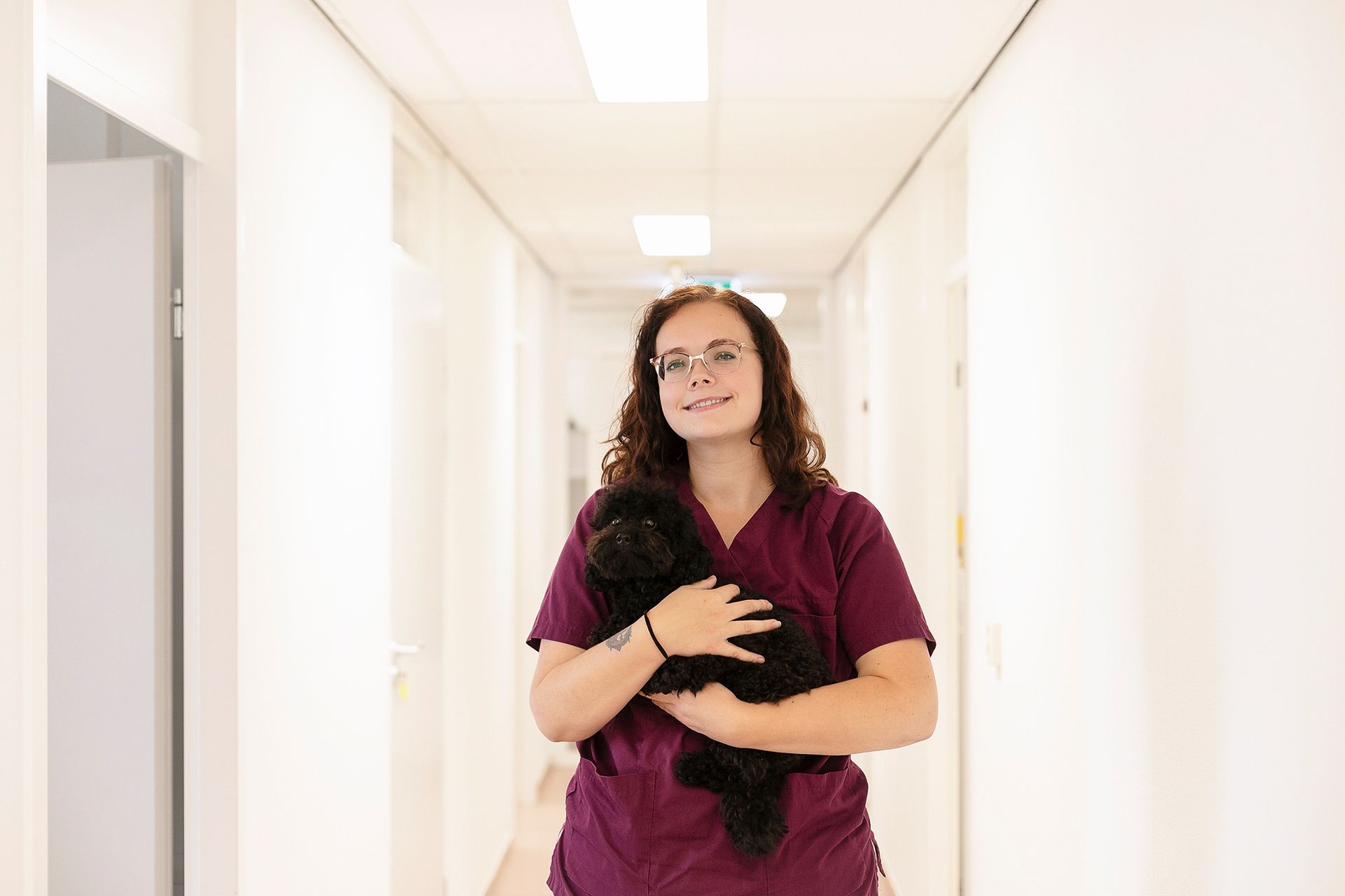 Een vrouw loopt door de gang en houdt een hond vast.