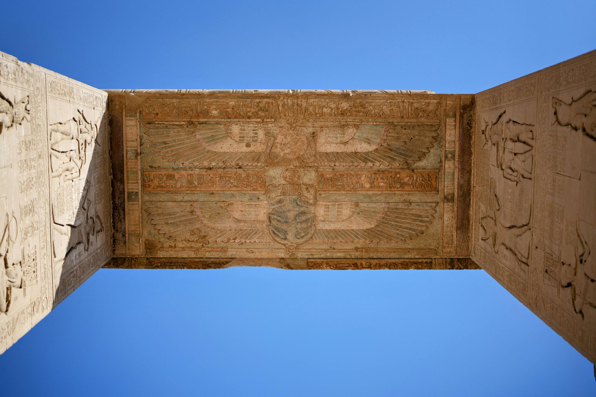 Stone lintel with carved hieroglyphs against a clear blue sky.