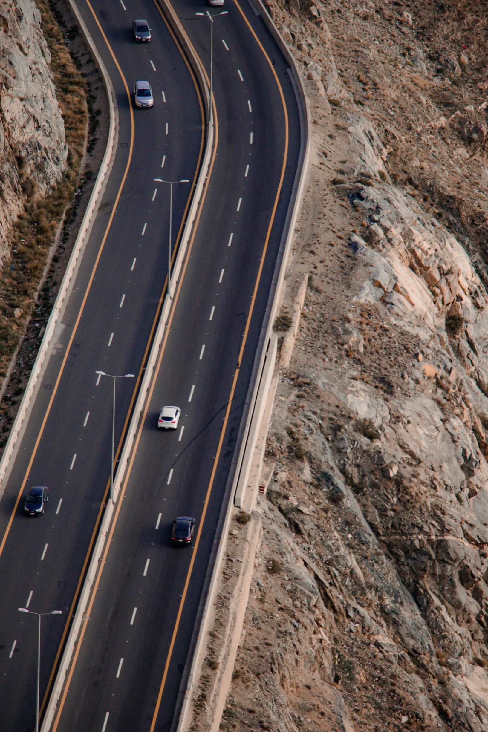 Winding highway through rocky mountains with cars driving on it.