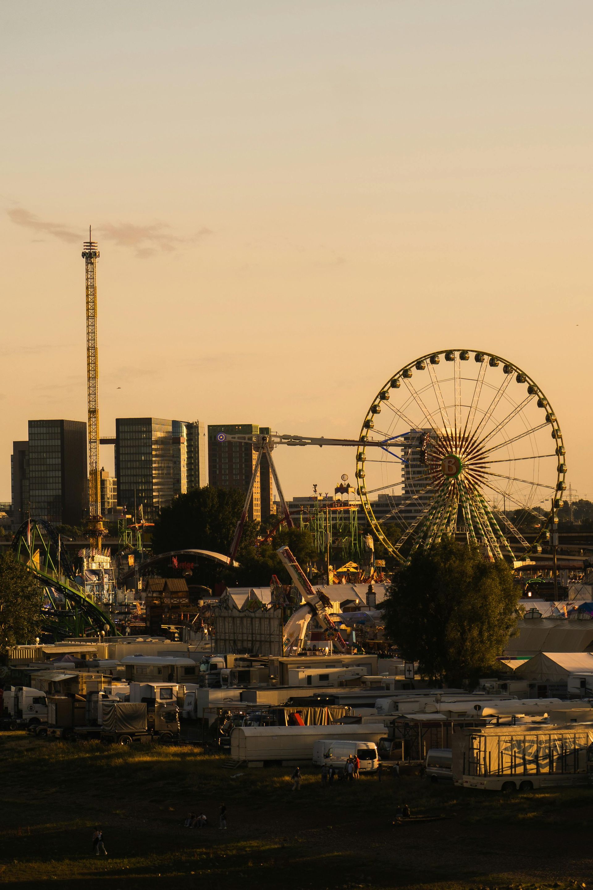 Amusement park with Ferris wheel, skyscrapers, and rides against a golden sunset sky.