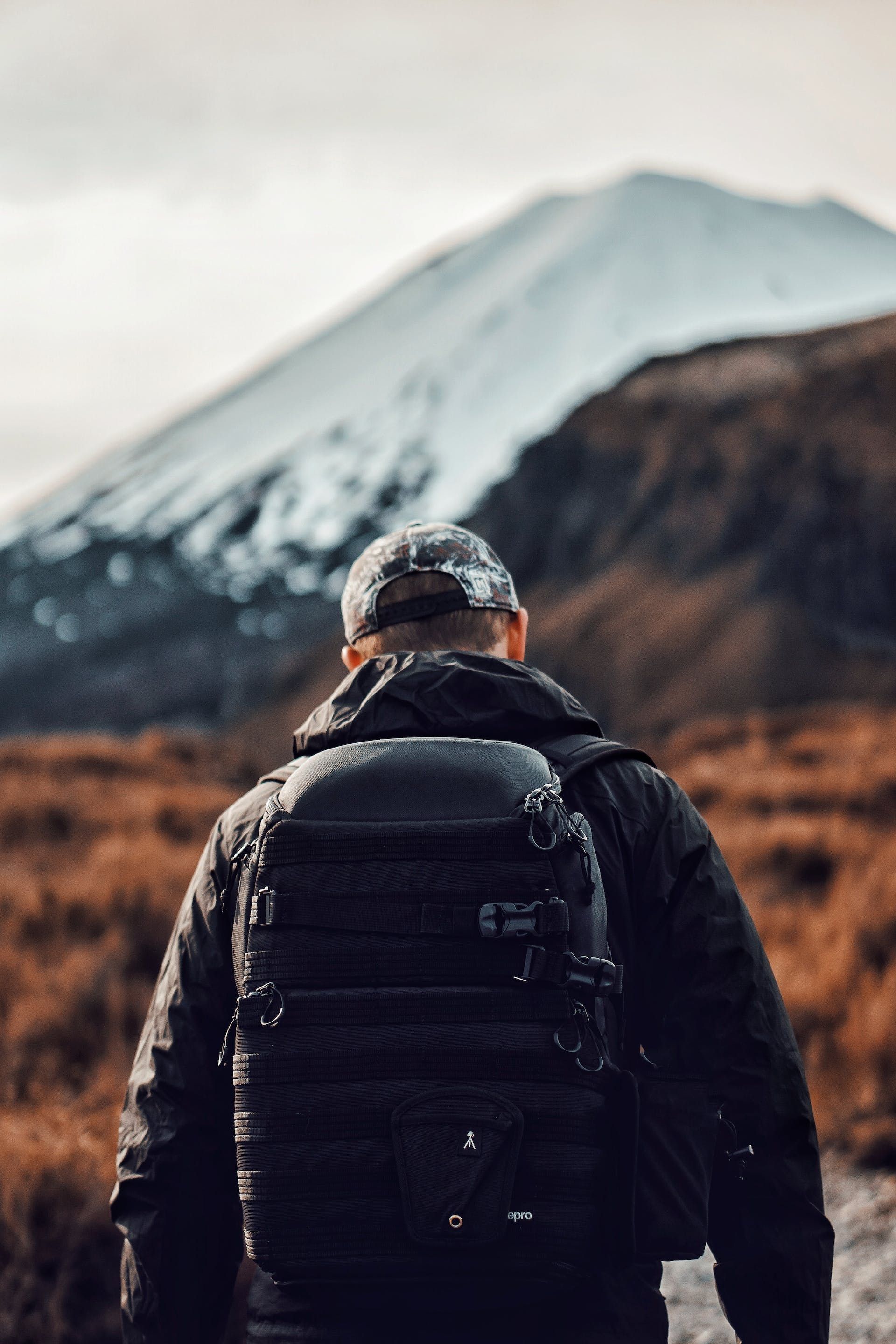 A man with a backpack is walking towards a mountain.