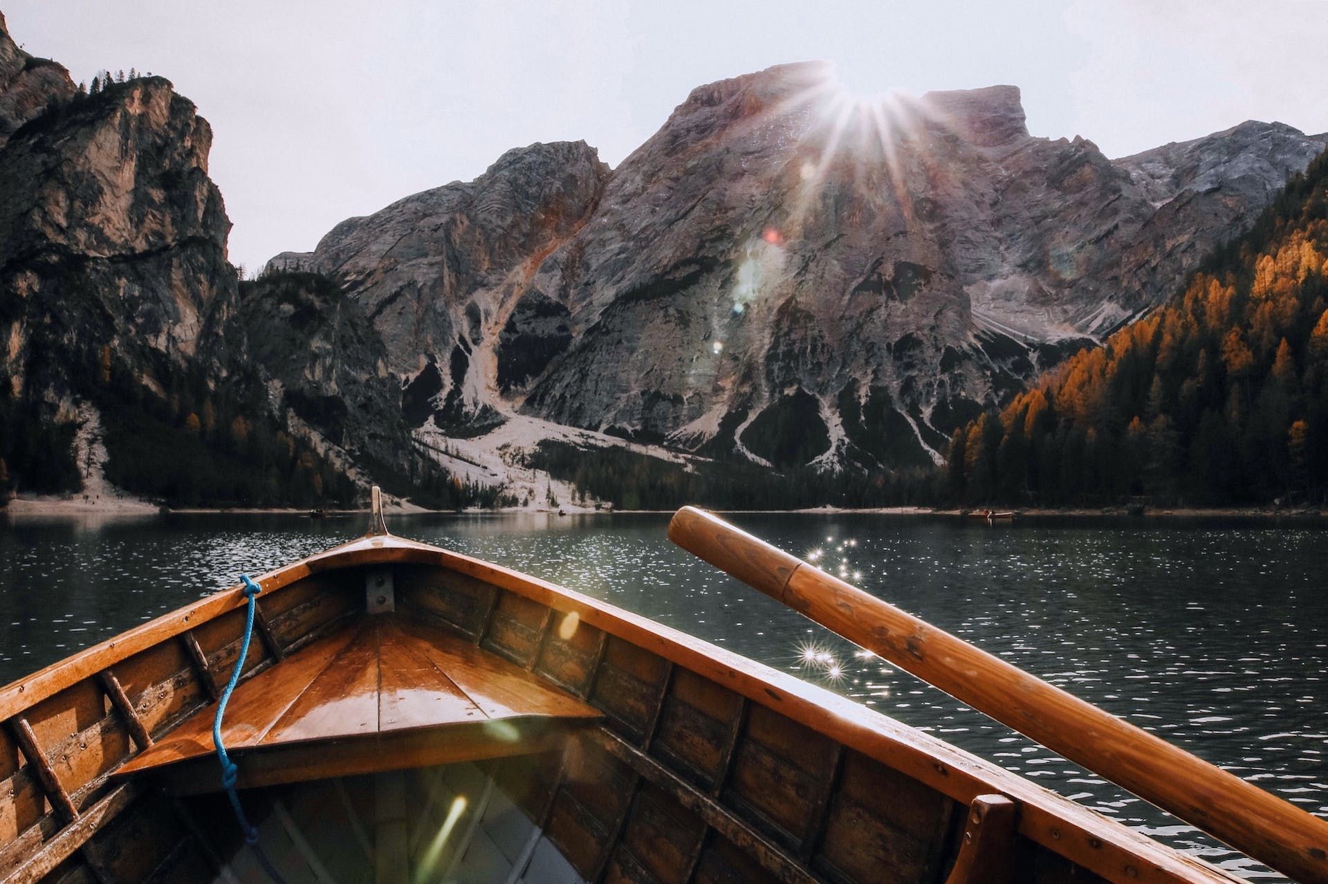 A wooden boat is floating on a lake with mountains in the background.