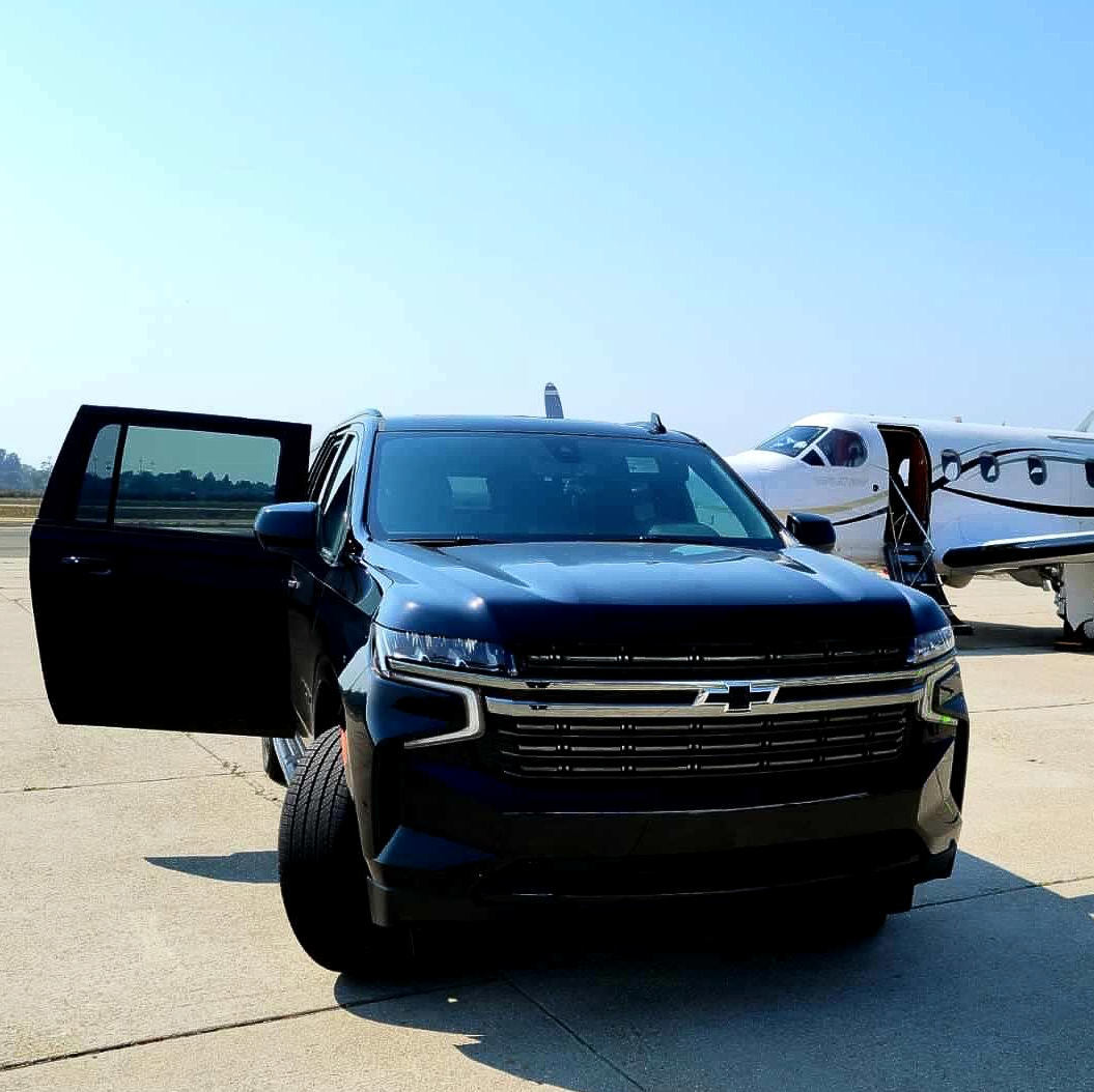 a black suv is parked next to a small plane