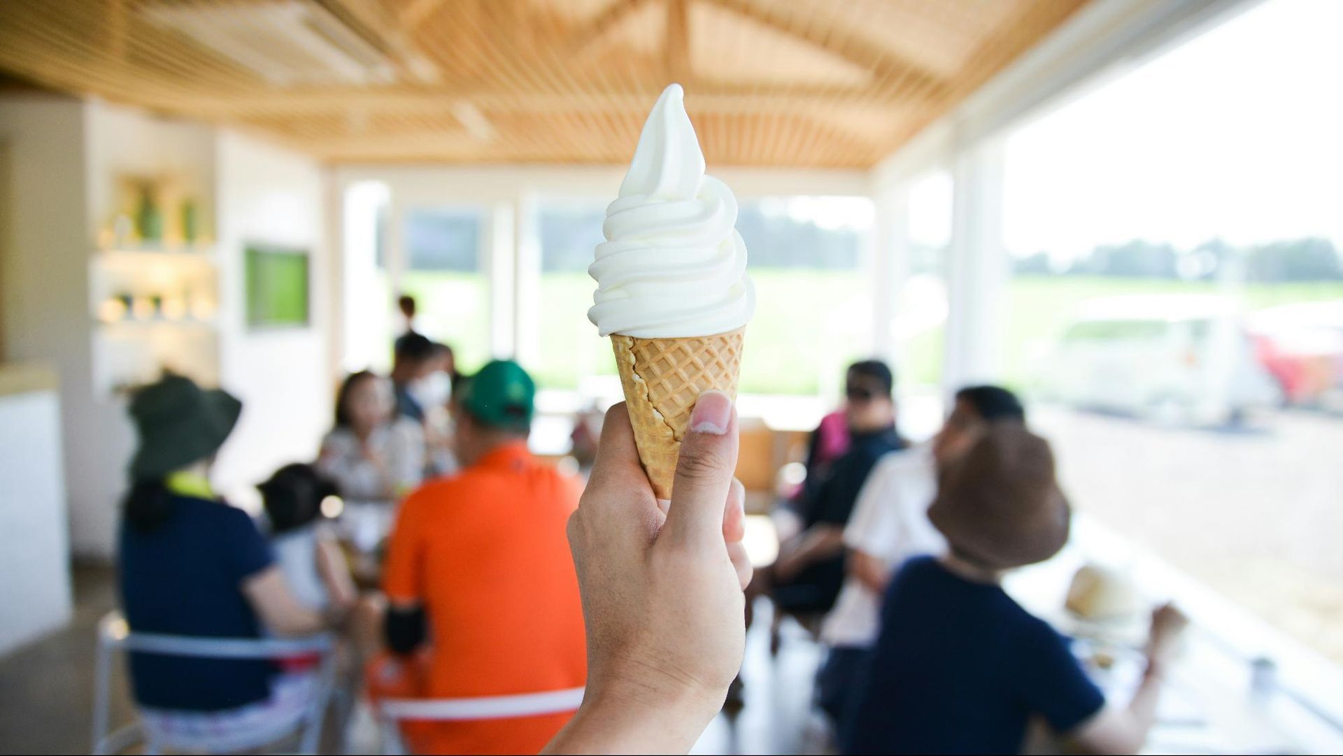 A hand holding a soft serve ice cream in a cone