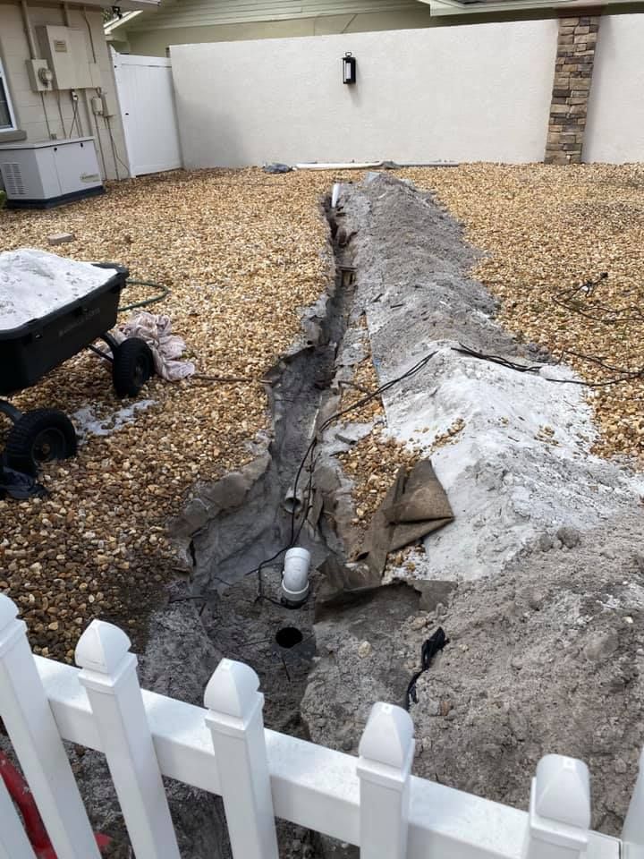 A white fence is surrounding a large pile of dirt in a backyard.