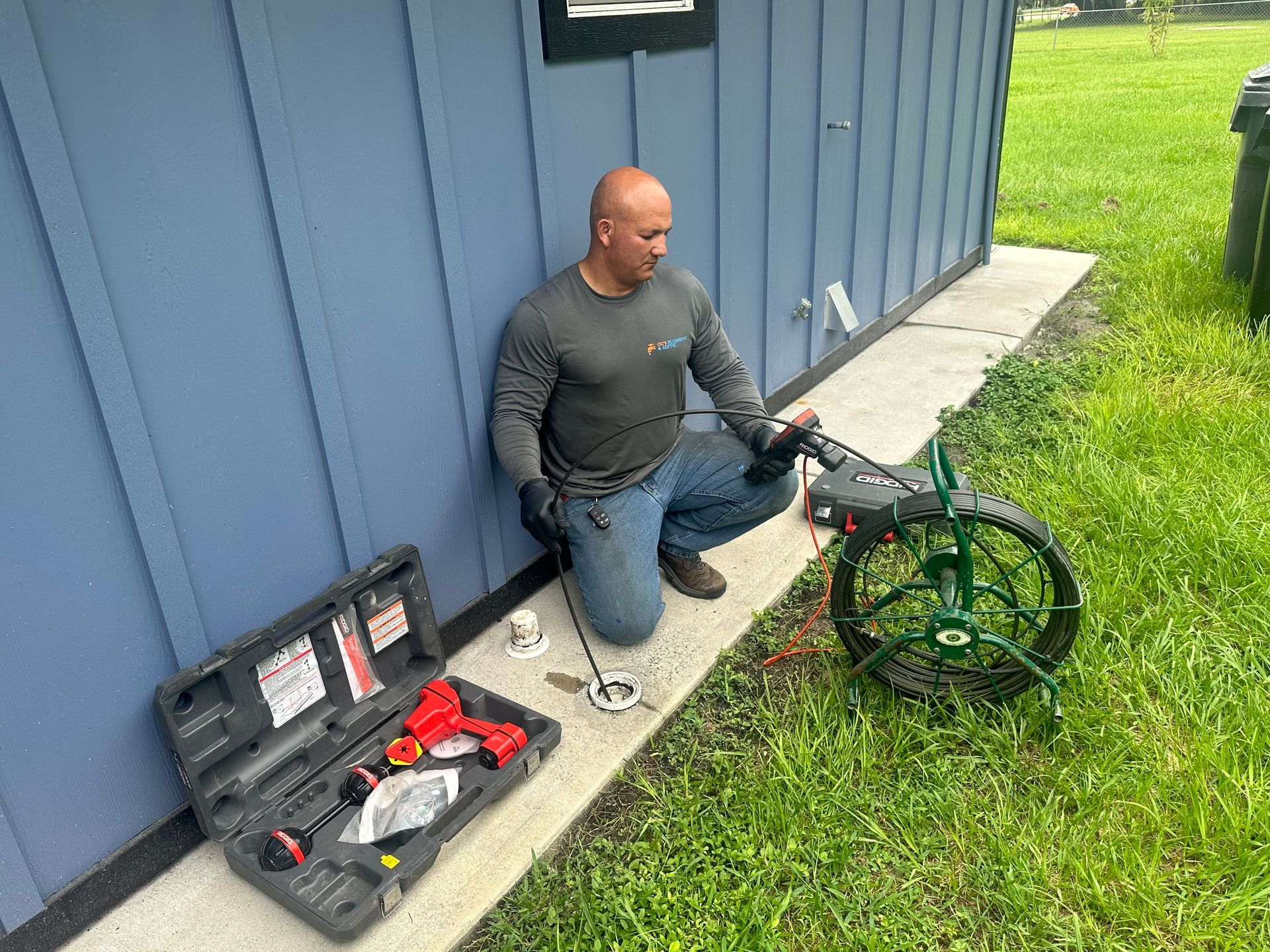 A man is kneeling down next to a hose and a toolbox.