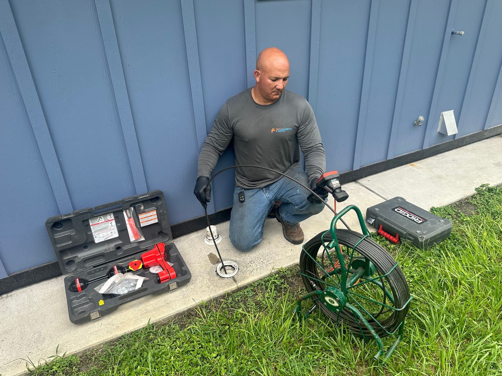 A man is kneeling down next to a drain camera.