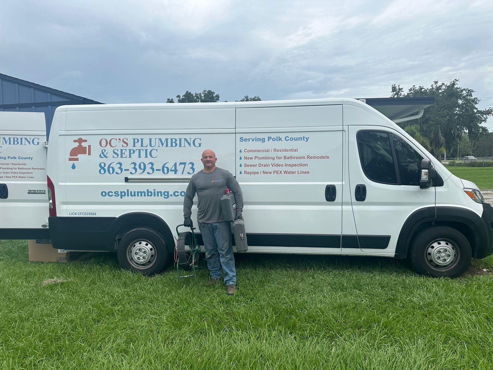 A man is standing in front of a white van for OC's plumbing & septic