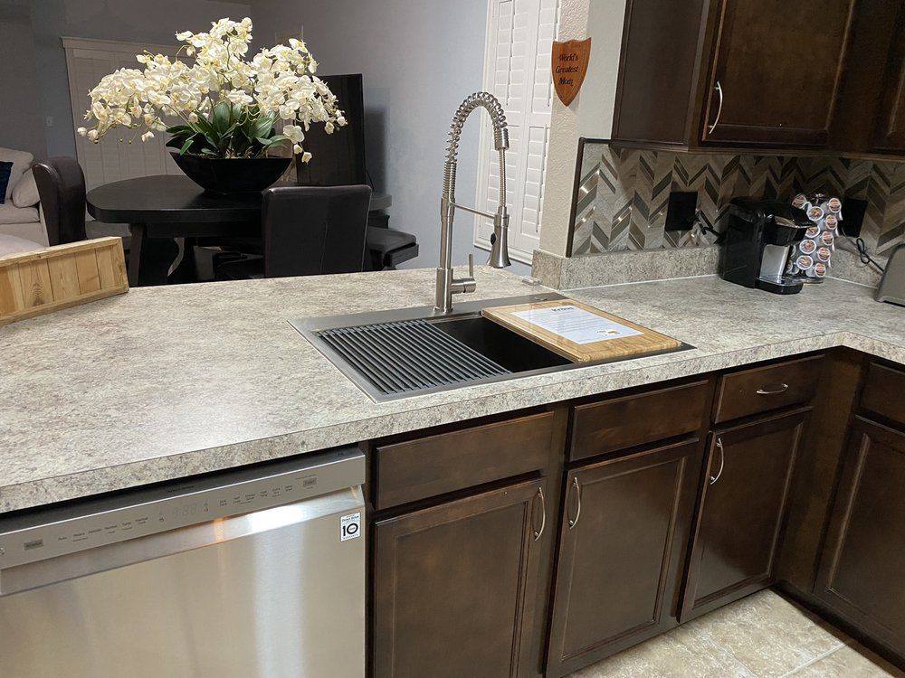 A kitchen with a sink , dishwasher , and flowers on the counter.