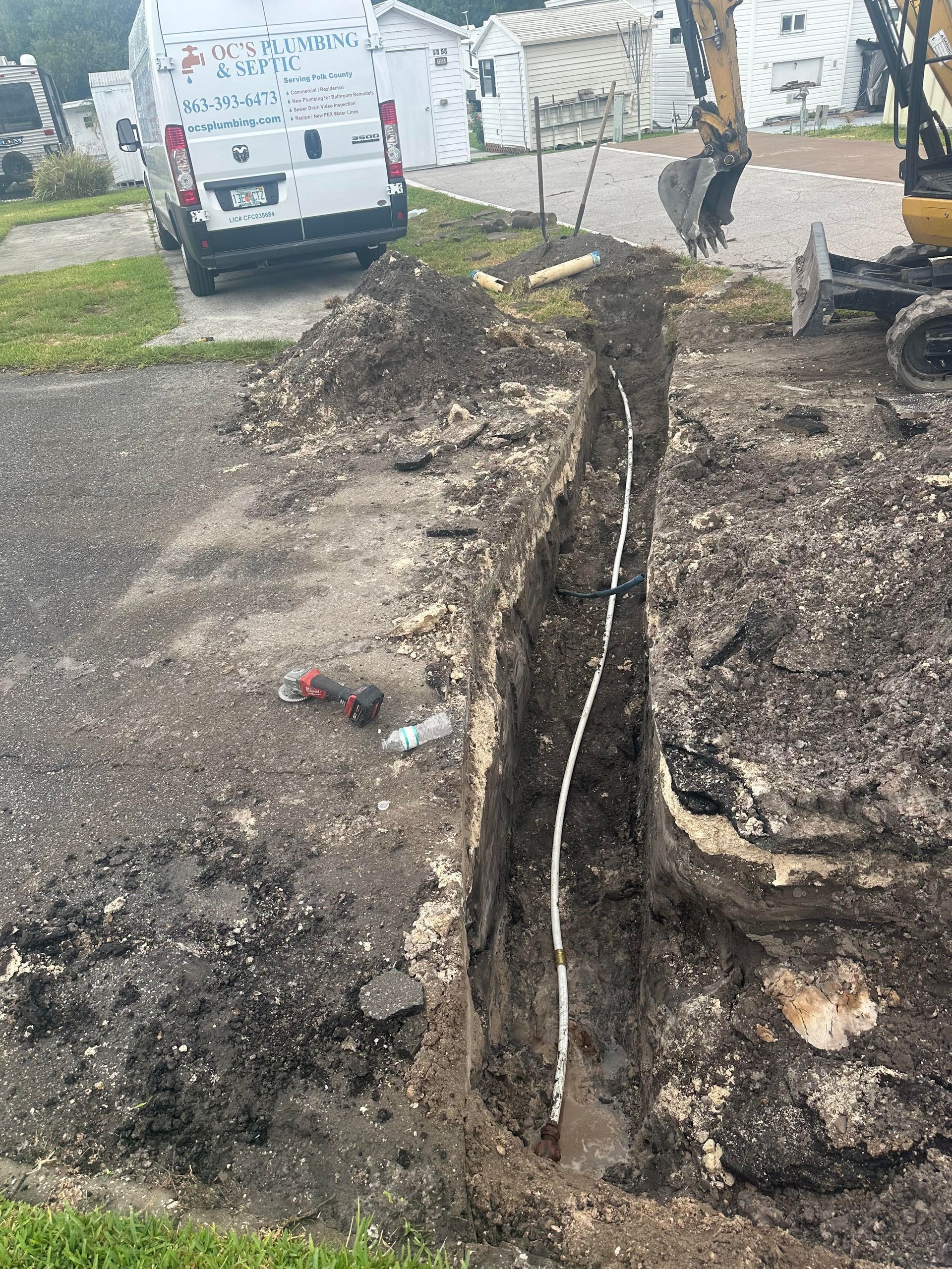 A white pipe is is in a large hole in the ground.