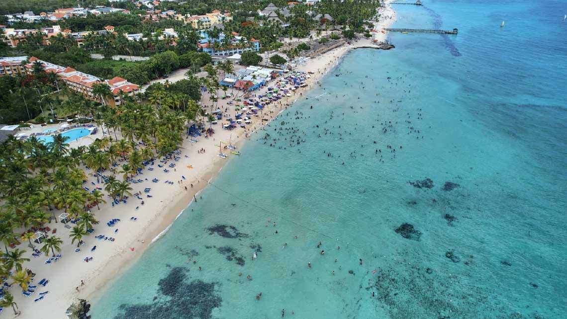 Una vista aérea de una playa con mucha gente nadando en el océano.