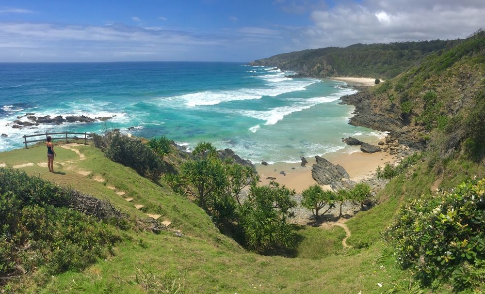 A Person Is Standing On A Cliff Overlooking A Beach — Hutchisons Tile Centre In Byron Bay, NSW