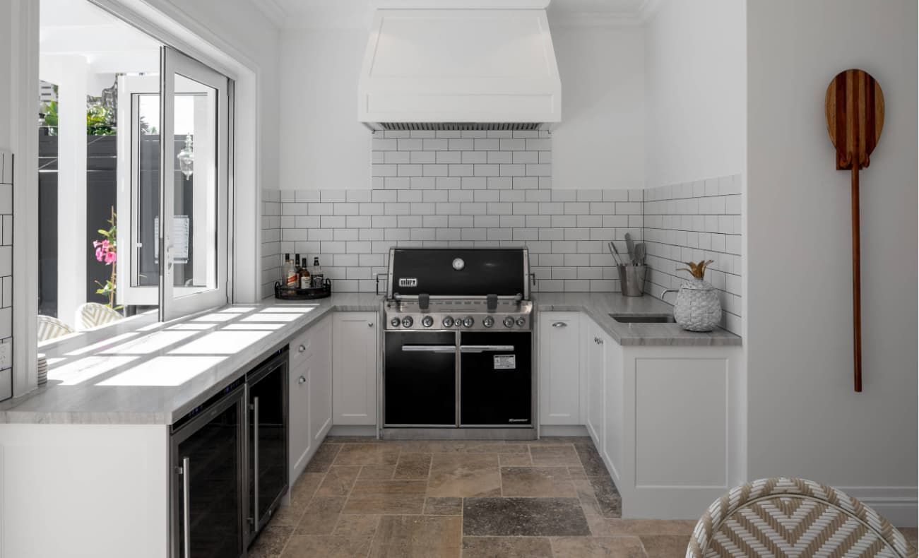 A Kitchen With White Cabinets, Black Appliances, A Grill And A Window — Hutchisons Tile Centre In Murwillumbah, NSW