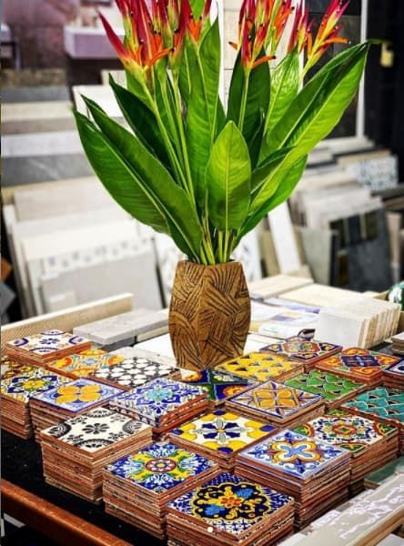 A Vase Of Flowers Is Sitting On Top Of A Table With Colorful Tiles — Hutchisons Tile Centre In Murwillumbah, NSW
