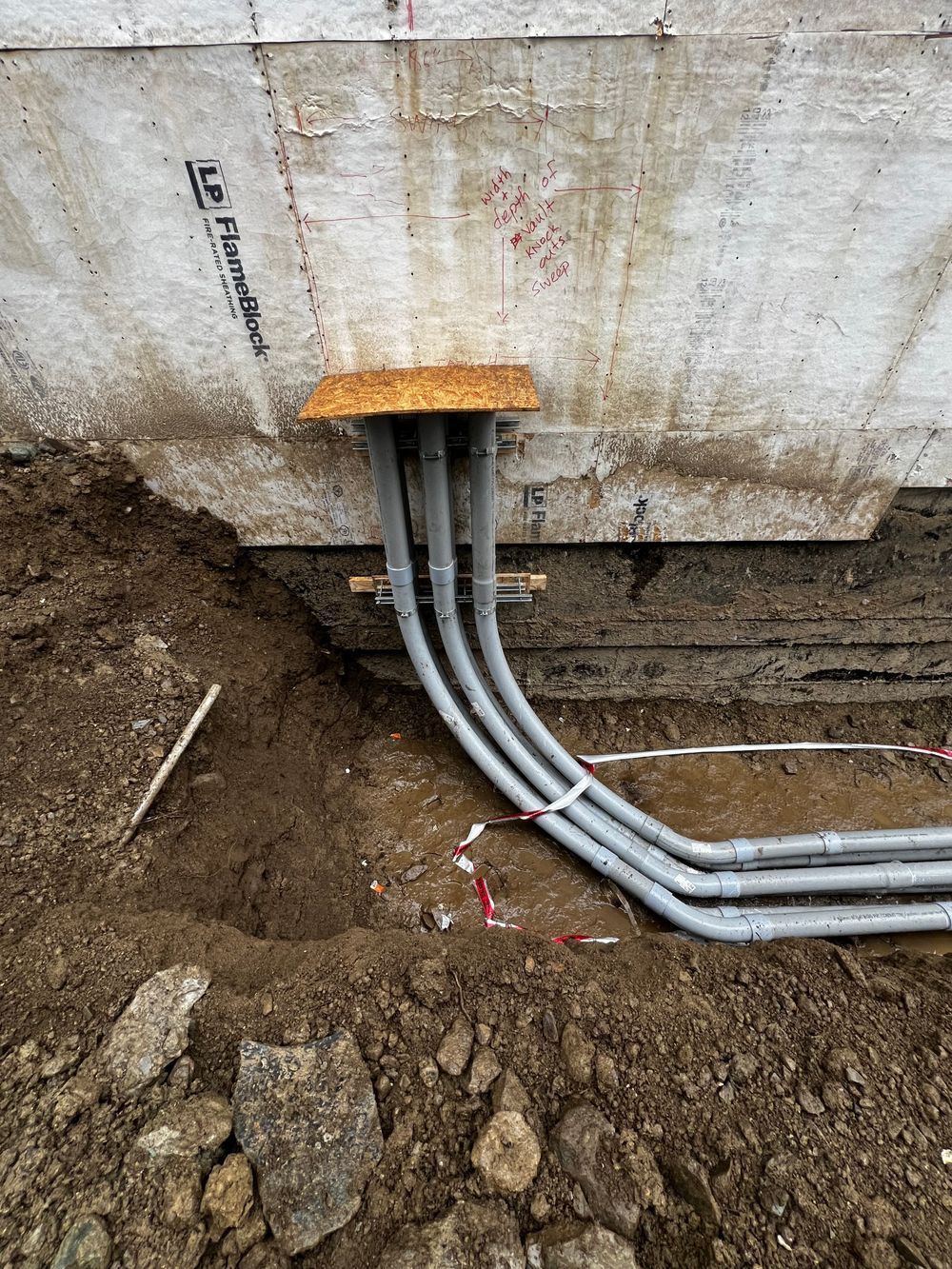 A bunch of electrical wires are coming out of a hole in the ground