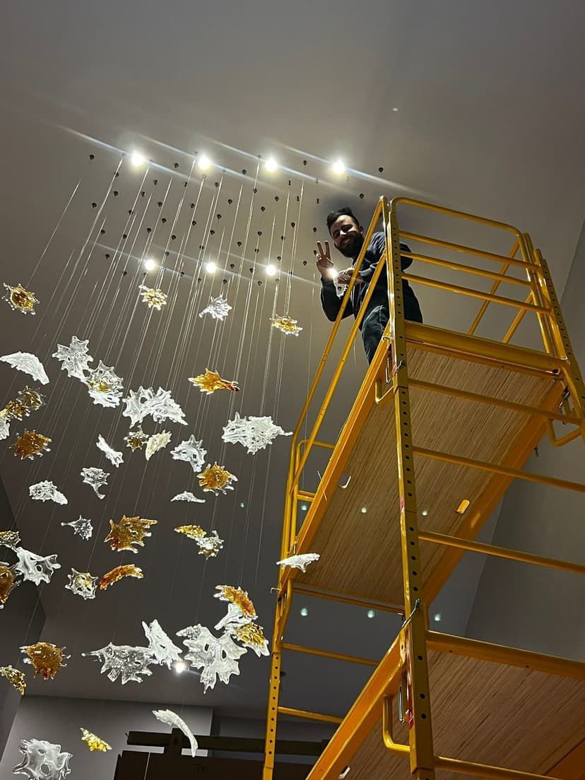 A man standing on a scaffolding looking up at a chandelier