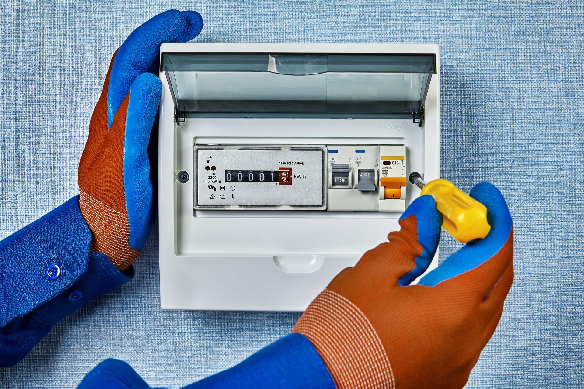 A person wearing blue gloves is working on an electrical box