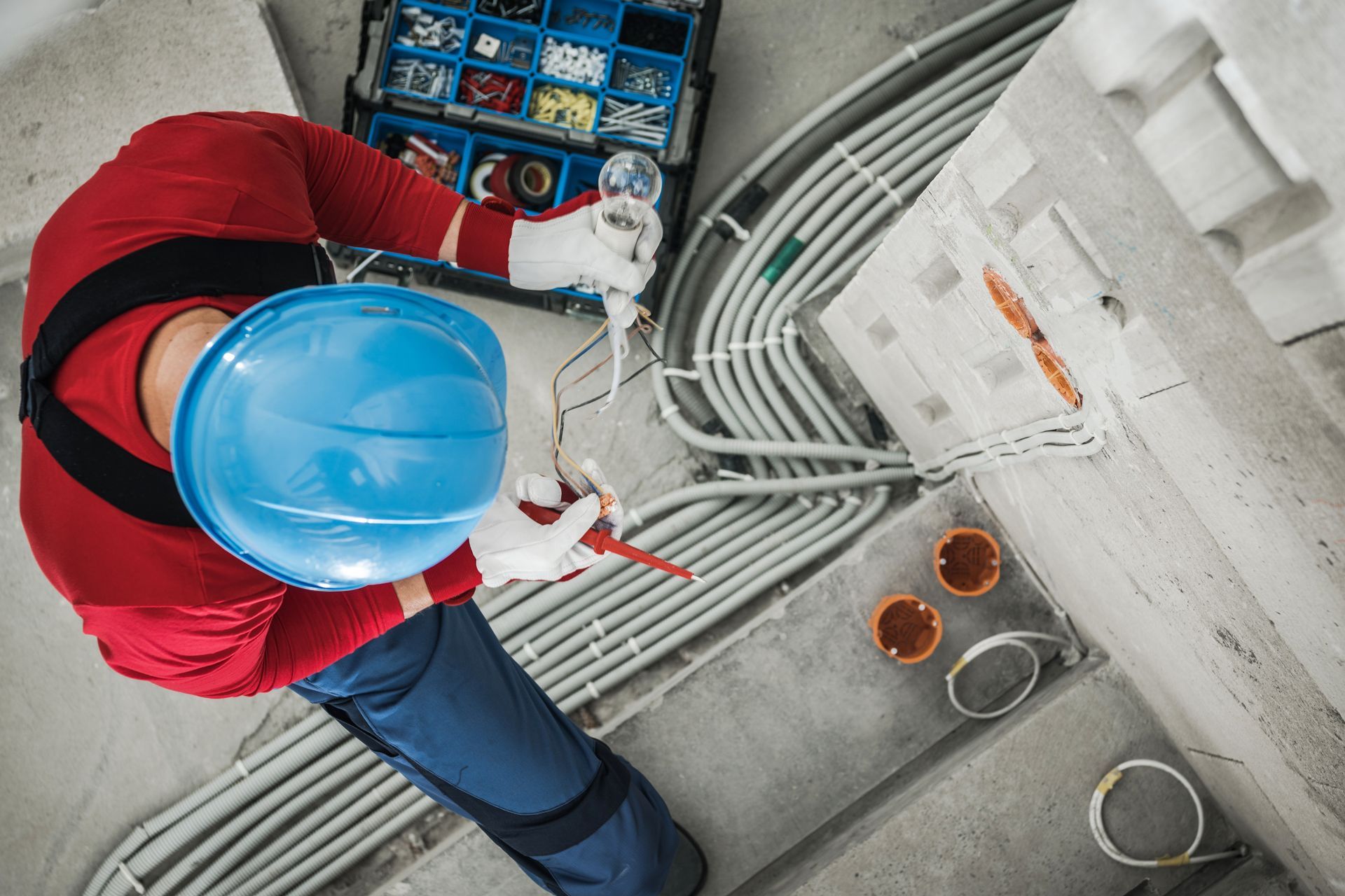 A man wearing a hard hat is working on electrical wires