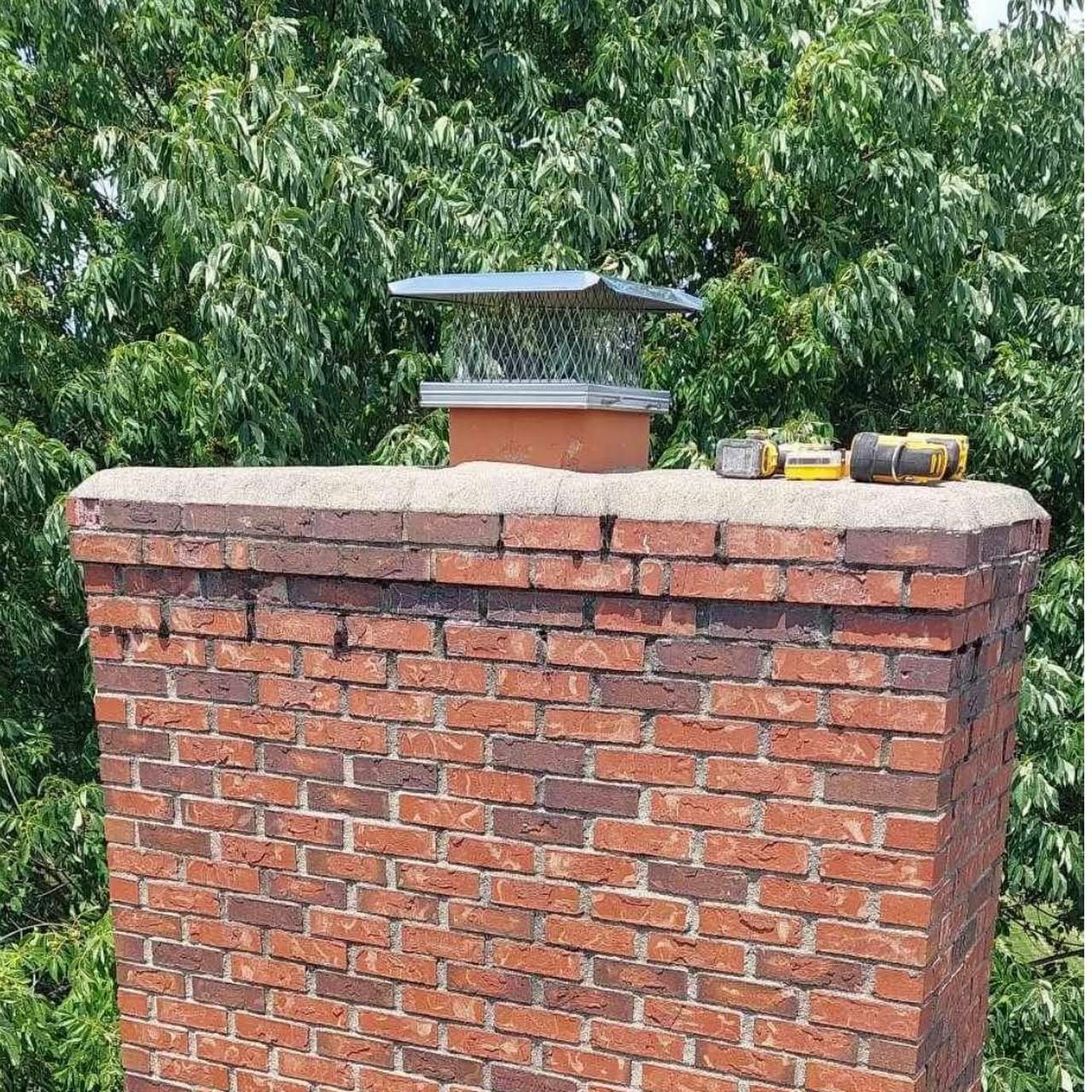 A brick chimney with a metal cap on top of it
