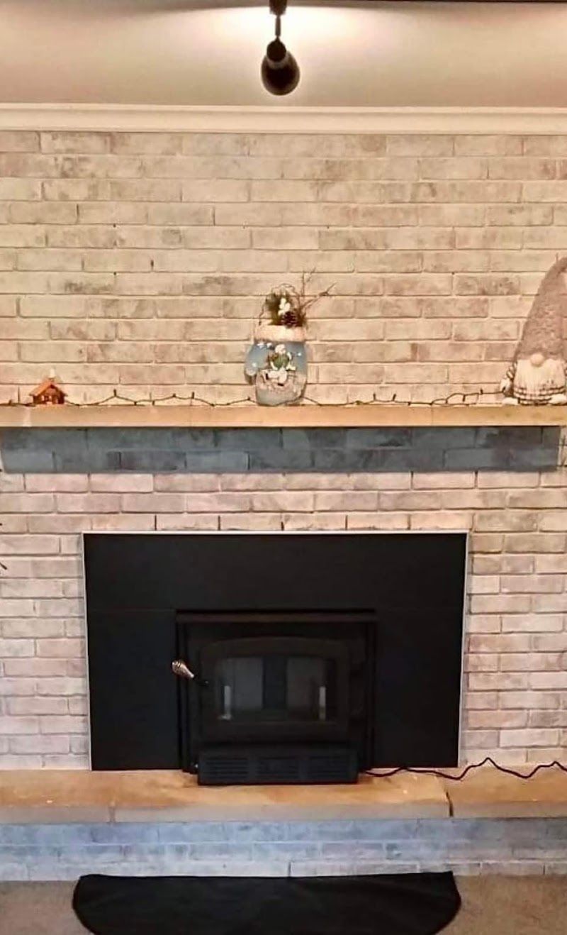 A living room with a fireplace and a brick wall.