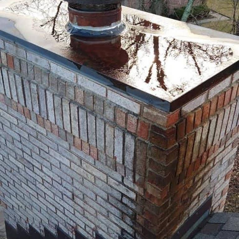 A brick chimney with a metal cap on top of it.