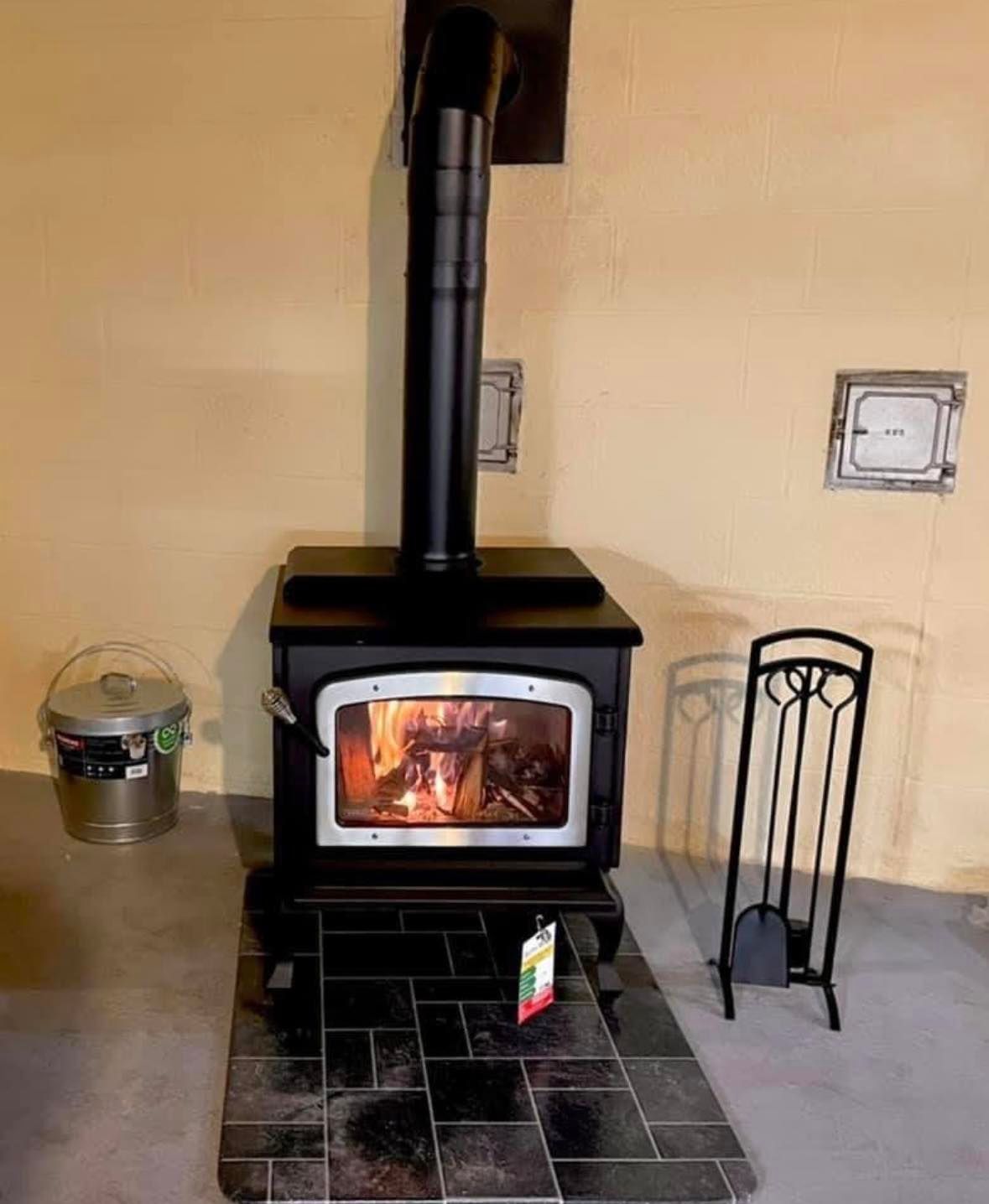 A wood stove is sitting on a tiled floor in a room.
