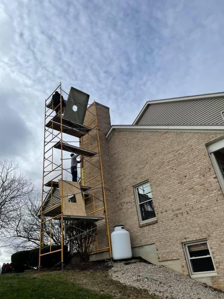 A man is standing on a scaffolding next to a brick building.