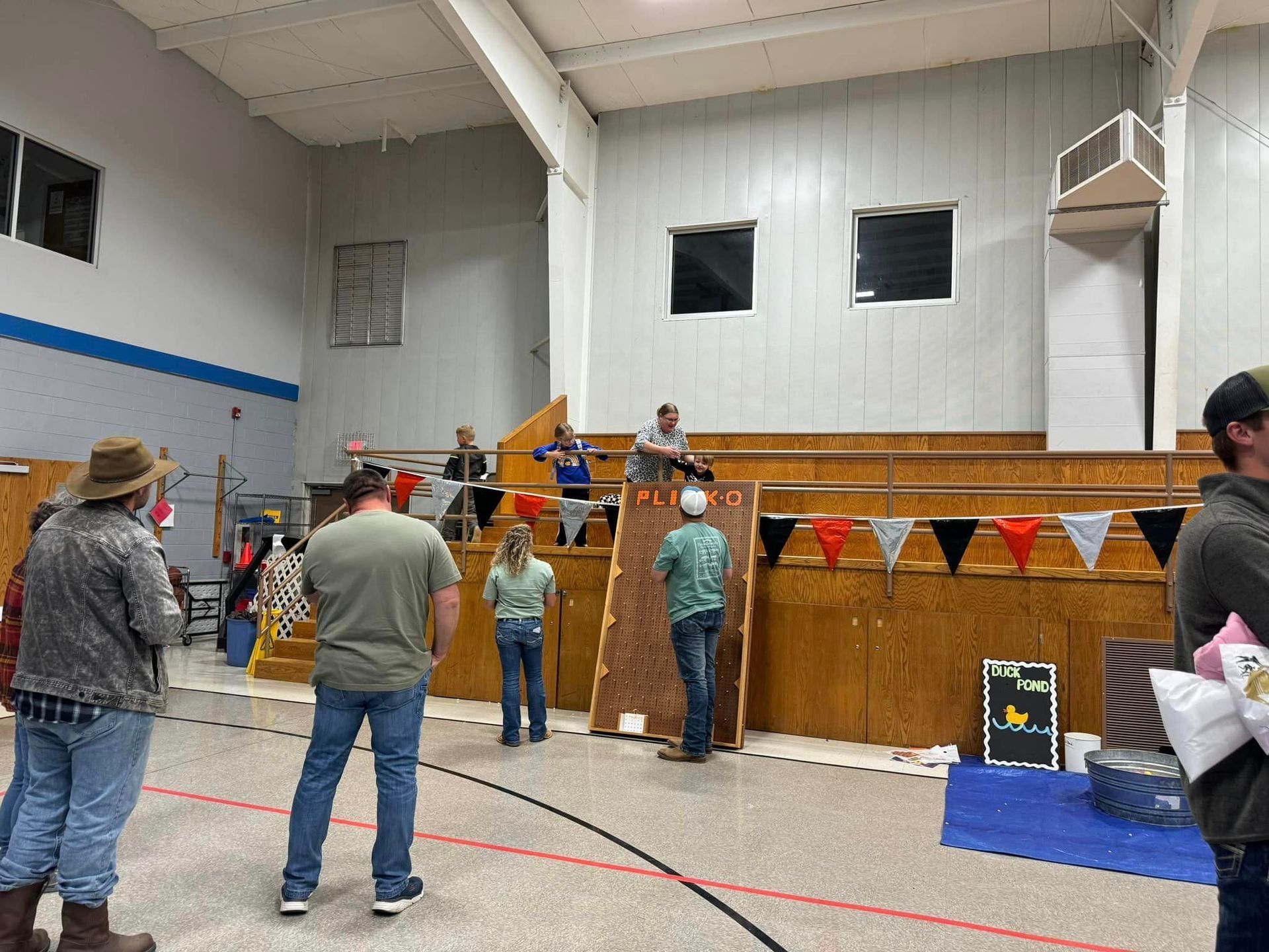 A group of people are standing in a gym watching a game at Octoberfest.