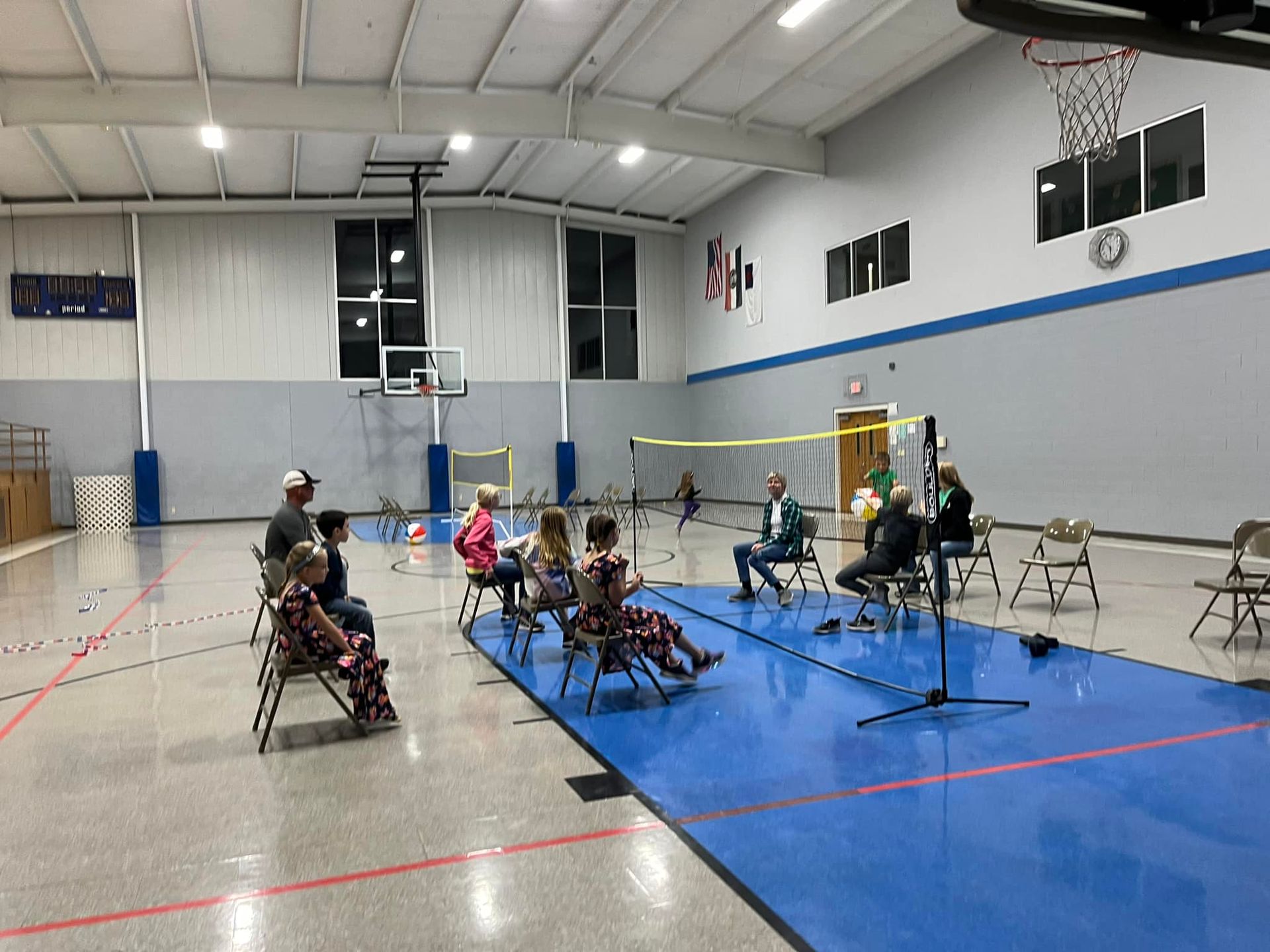 A group of people are playing chair volleyball in the gym during a PTL meeting.