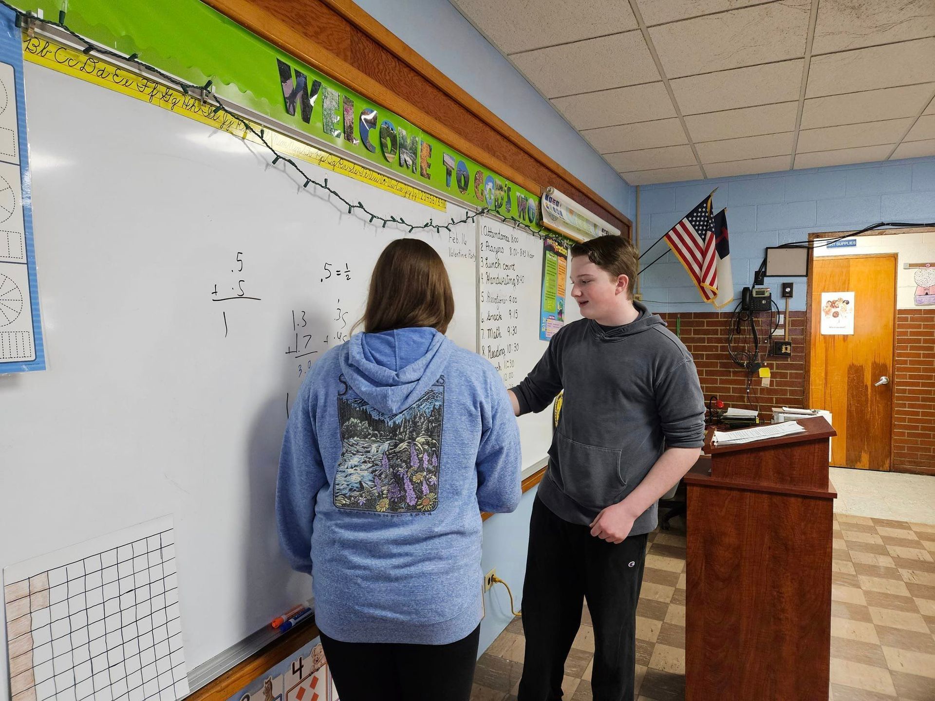 Middle school students standing in front of a whiteboard in a classroom, teaching younger grades during Lutheran Schools Week.
