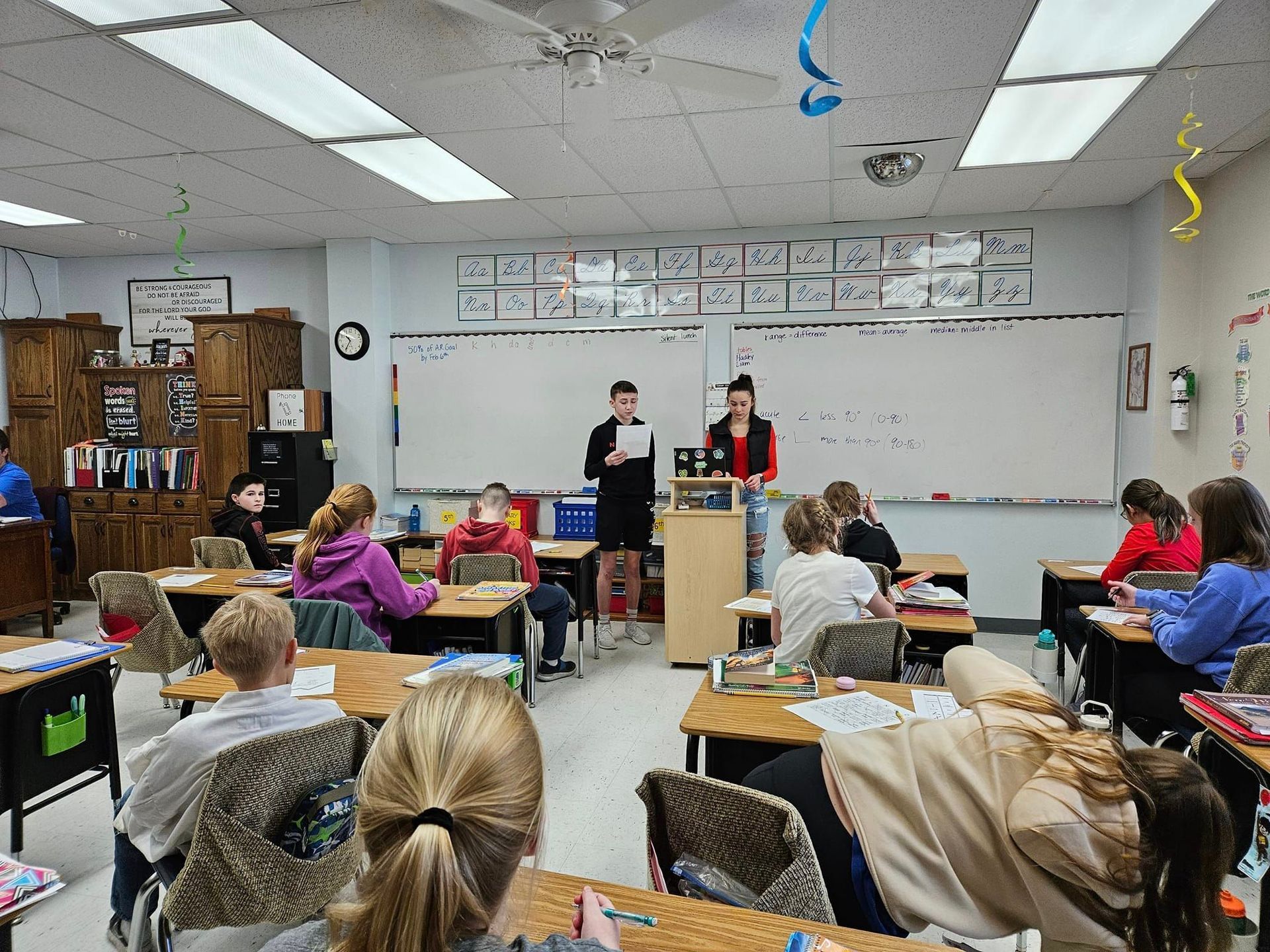 Middle school students teaching younger students in a classroom.
